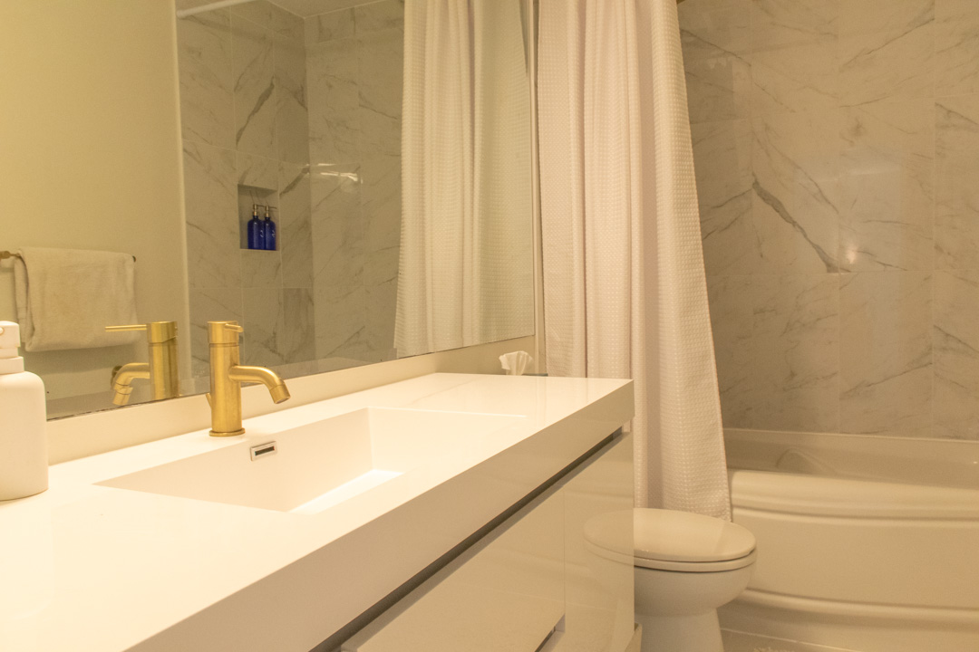 Renovated guest bathroom with marble tile and gold fixtures